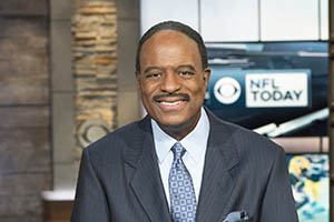 James Brown, NFL announcer, in suit sitting at desk.